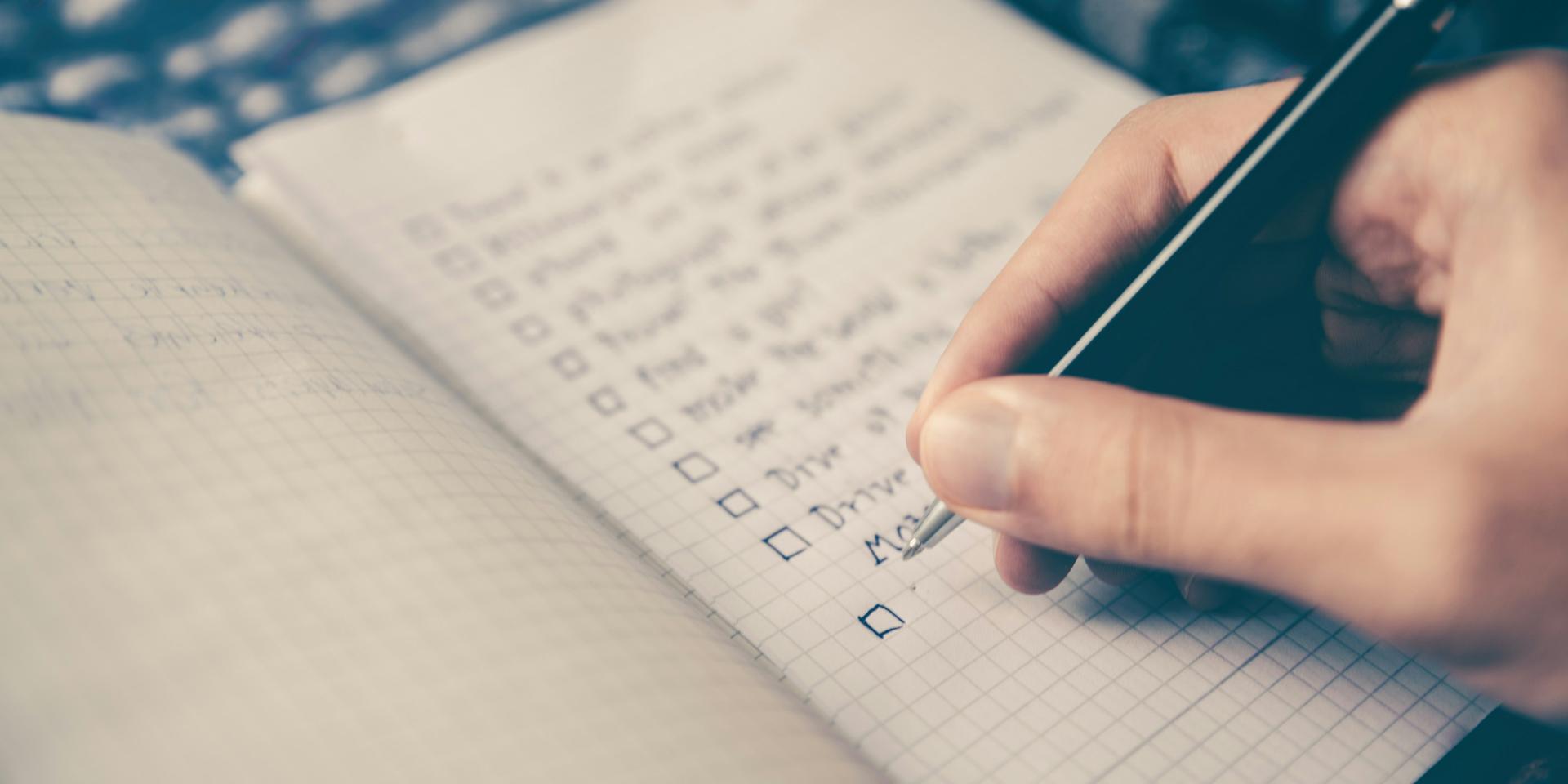 Personne écrivant une checklist dans un cahier